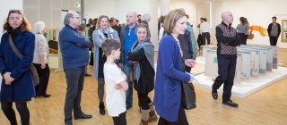 Groep mensen die aandachtig door expositie loopt.