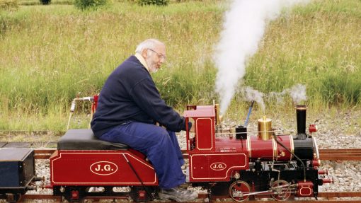 Jan Dirk van der Burg sits on red model train with locomotive